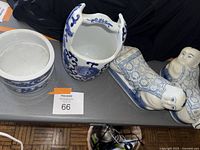 Top-down view showing all four items on a table: two reclining Buddha pillows, ceramic bowl, and water bucket with handle.