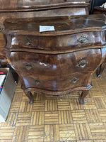 Front view of burlwood Bombay chest of drawers showing the three drawers and curved design.