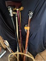 Full view of collection showing various walking canes with different handles and the wicker basket holding them.