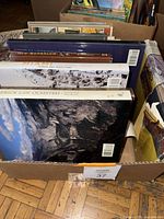 Photo showing the top edges and covers of various large books, mostly decorated hardcover books related to decorating and architecture.