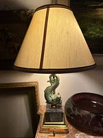 Full view of lamp showing fish sculpture, marble base, brass accents, and shade