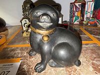 Front view of the antique Japanese bronze dog sculpture showcasing facial features, posture, and collar with bells.