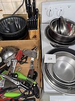 Photo showing bundled and round cake pans stacked, mixing bowls with lids and the Master Chef wooden knife block with knives.