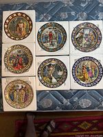 Full view of 7 Wedgwood collectible medieval plates arranged on fabric surface, showcasing colorful detailed illustrations and floral borders.