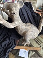 Front angle view of the ceramic animal figurine showing etched patterns, head with open mouth and tongue, and feet.