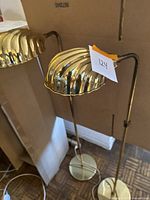 Pair of mid century brass floor lamps with ribbed shell-shaped shades, tall and slender with round bases