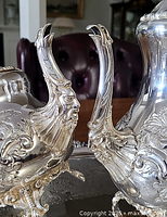 Close-up of two spouts featuring bearded face ornamentation