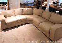 Three-piece beige faux leather L-shaped sectional couch shown in a room.