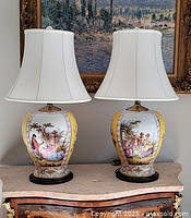 Front view of both lamps on marble-topped cabinet with painting in background