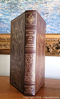 Front and spine view of the leather bound book with gold embossed decorations.