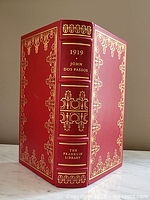 Front and spine of the red leather bound book showing gold embossed decorations and titles.
