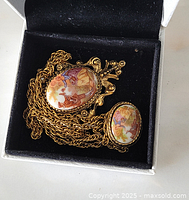 Close-up of Limoges porcelain cameo pendant and clasp on gold-tone chain inside black jewelry box.