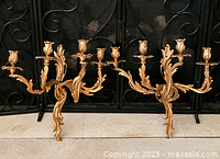 Pair of gold-tone four-arm metal wall sconces displayed side by side against fireplace screen