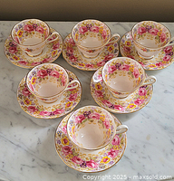 Top view of all 6 Royal Albert Serena cups and saucers arranged on a marble surface.