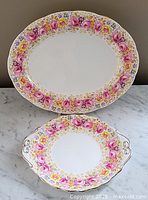 Two-piece set showing the platter standing behind the cake plate on marble surface.