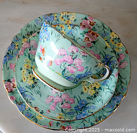 Stacked Shelley teacup, saucer, and dinner plate with floral pattern and gold rims.