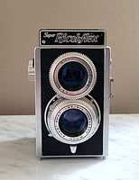 Front view of Super Ricohflex TLR camera showing twin lenses and branding.