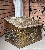 View of the top and two decorated sides showing detailed repoussé relief scenes of people and ornate borders on a brass box.