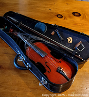 Wide view of open case showing violin, bow, loose horsehair and accessories