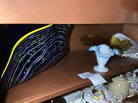 Shelf with four pieces of art glass including rectangular magazine holder, small vase, pedestal dish, and fluted dish