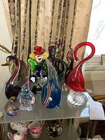 Full set of eight assorted colorful art glass figures arranged on a shelf including animals and clown figures.