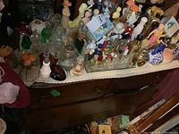 Wide angle view showing multiple Avon perfume bottles and glass collectibles on dresser top.