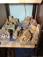 Group of nine resin house collectible figures arranged on a shelf showing variety in style and size