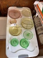 Full view of pink cake plate, yellow serving dishes, two green juicers, and green ashtray arranged on table