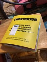 Yellow Chesterton labeled binder containing vintage comic books on a wooden surface.