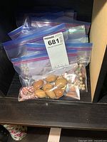 Photo of several ziplock bags containing assorted costume jewelry items, including oval beige/brown linked pieces and a pink beaded bracelet.