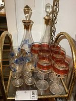 Photo showing 2 glass decanters with stoppers and 11 assorted glasses on tray.