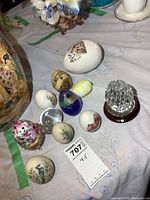 Overall view of eleven egg collectibles on table showing variety in material, design, and size