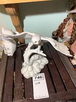 Front and side view of white porcelain owl figurine with outstretched wings perched on a branch, featuring detailed feathers and amber eyes.