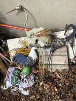 Four large metal bird sculptures shown leaning against a wall outdoors, each with different metal and painted designs, some rust and wear visible