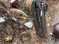 Photo of black metal garden tower and metal whirligig fans with visible surface rust and outdoor debris