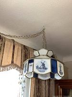 Side angle of the hanging lamp showing the blue and white glass panels with windmill artwork and brass-tone framing.
