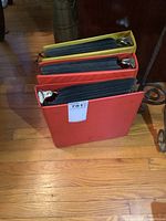 Three closed binders standing on the floor with one label showing.