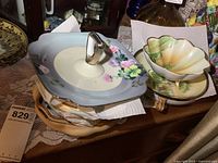 Display of several vintage Nippon china dishes including a light blue square serving dish with lid and silver-tone handle, and a small green and peach scalloped bowl.
