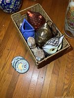 Basket containing various owl figurines made of ceramic, metal, and shells