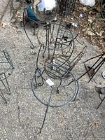 Image showing multiple metal plant stands and the spherical glass-like ball sitting on top of one stand.