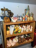 Overall view of wooden shelf with large collection of varied salt and pepper shakers including animal shapes, towers, and novelty items.