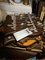 Large wooden spoon rack with multiple collector spoons secured by fabric strips.