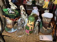 Photo of shelf with various decorative items including ceramic teapot/vase with deer, figurines, and crystal bells