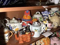 Middle shelf with collection of various ceramic teapots, medium to extra large size with assorted styles and motifs