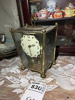 Vintage brass clock on lace tablecloth with wooden cabinet background, showing full clock and brass detailing