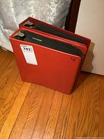 Two red binders closed, showing exterior condition and size.