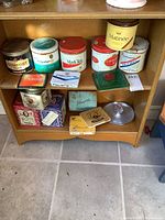 Wide view of all tins and ashtray displayed on shelf showing round and flat tins with vintage branding.
