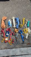 Overview of assorted nylon ropes in various colors including orange, white, blue, yellow, and green. Several red and blue straps with yellow and metal hooks. Also shows multiple accessory hooks.
