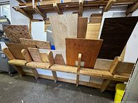 Wide shot showing multiple wood sheets including plywood, presswood, and chipboard arranged vertically in a rack
