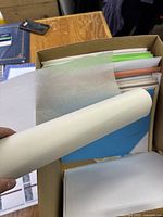 Box of assorted papers with neon colored printer paper, translucent sheets, and colored cardstock sheets.